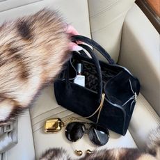 A photo of Rosie Huntington Whiteley's suede bag with a bottle of perfume inside