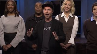 Dana Carvey doing an Elon Musk Impression on Saturday Night Live with the Season 50 Cast behind him