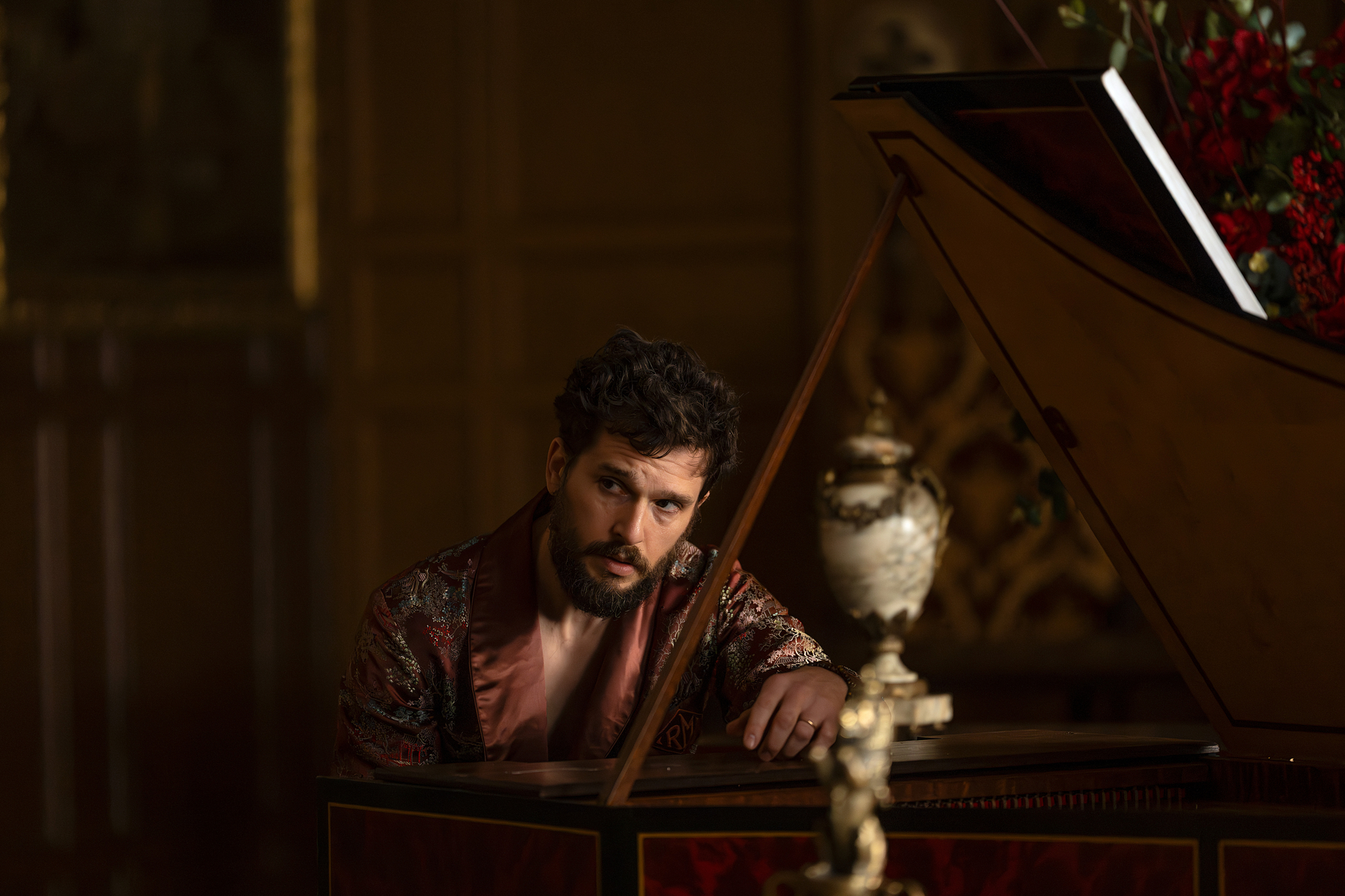 kit harrington as henry muck wearing a rob at a grand piano in industry season 4