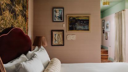 A rose and mint green-tinted hotel room, decorated with tapestries, framed artworks, upholstered headboards, and more romantic touches.