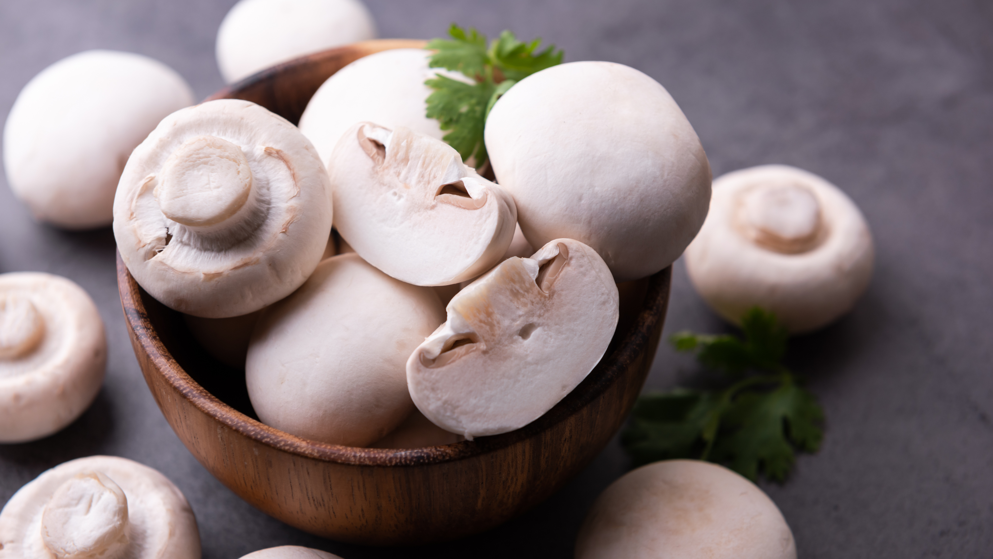 Fresh white mushrooms in wooden bowl.