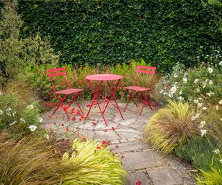 circular paved patio with red metal garden table and chairs