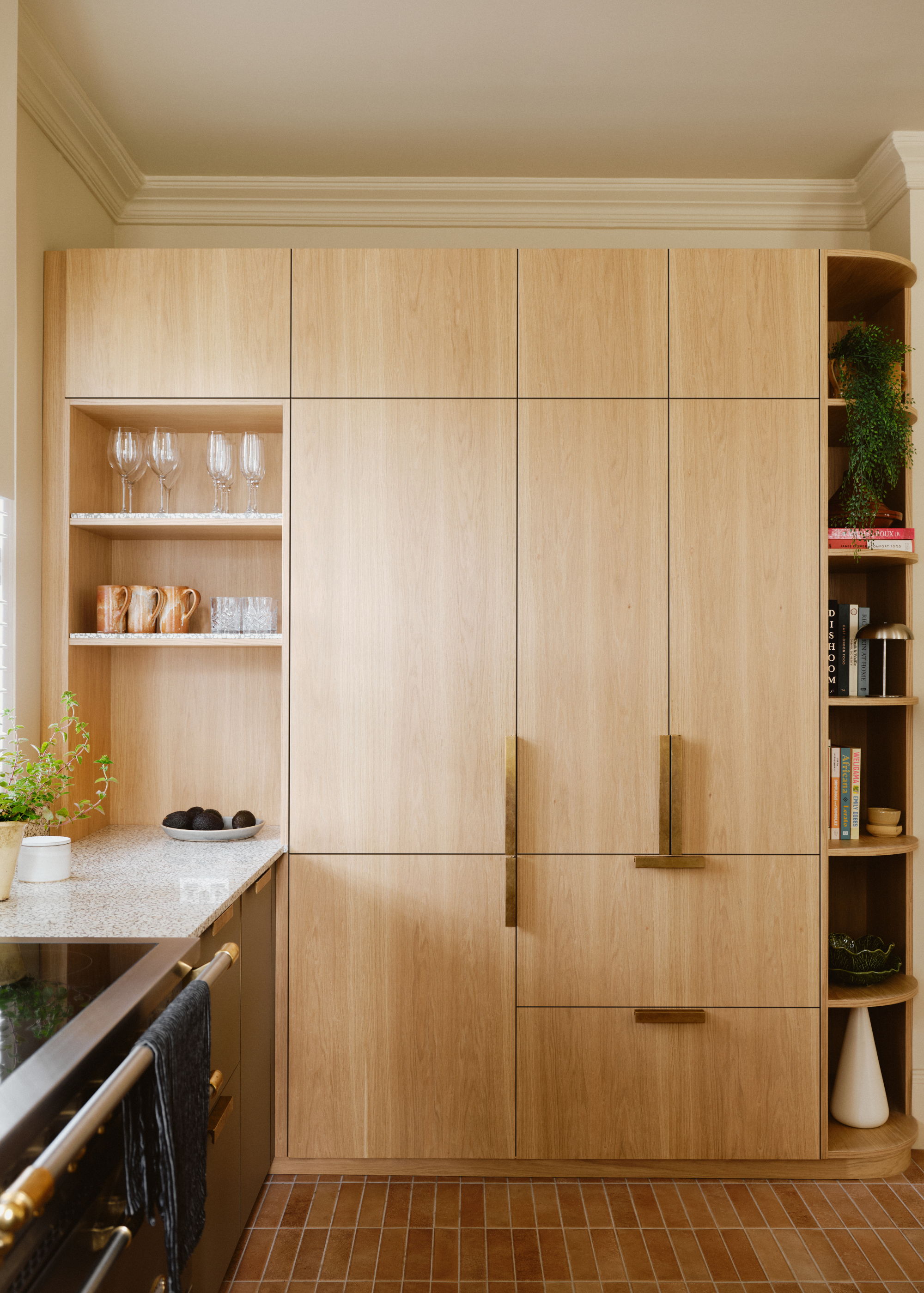light wooden cabinetry with brass handles in a brick floor kitchen