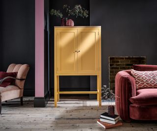 living room with dark grey walls, yellow storage cabinet and pink chairs