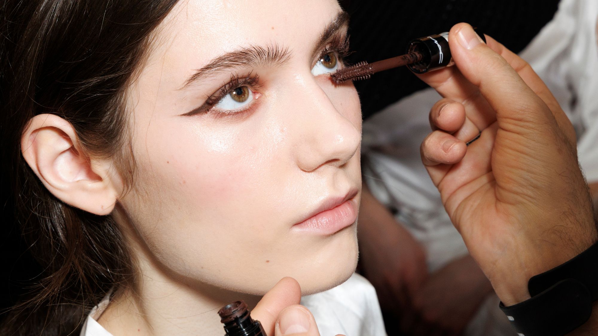 model backstage getting brown mascara applied