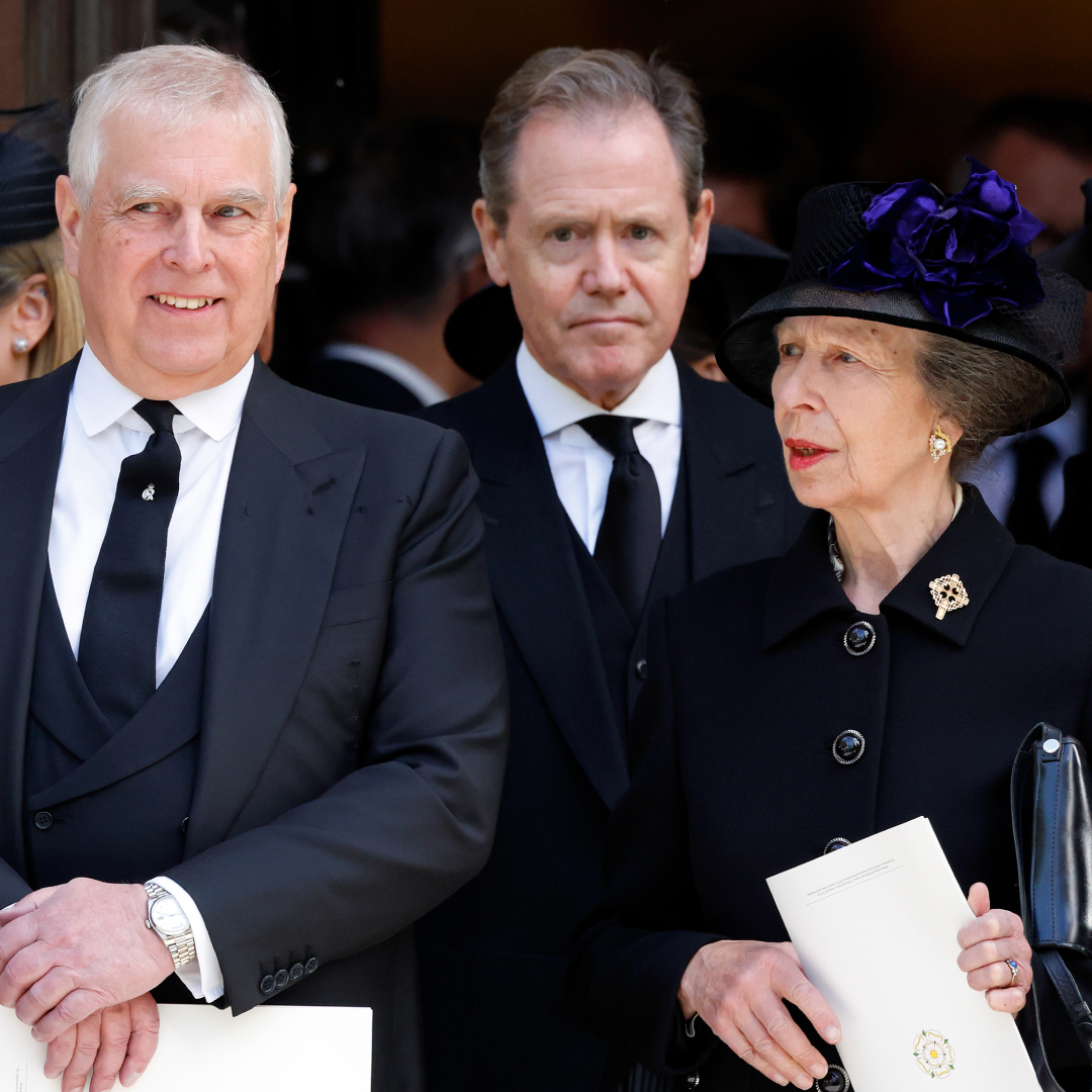 Prince Andrew wears a suit and has gray hair and smirks while his sister Princess Anne wears a black coat and hat and has red lipstick on