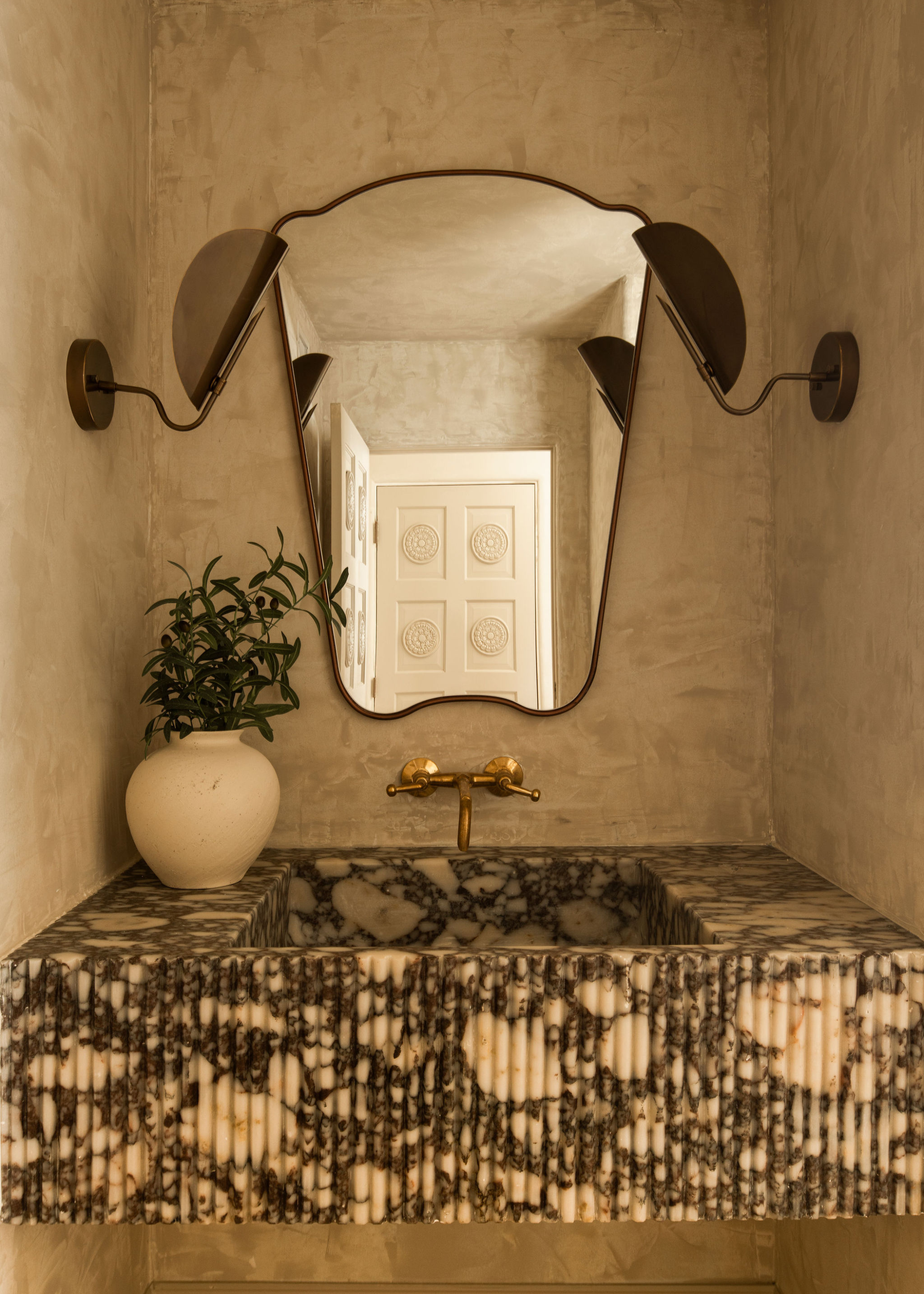 A powder bathroom with a limewash wall behind the sink