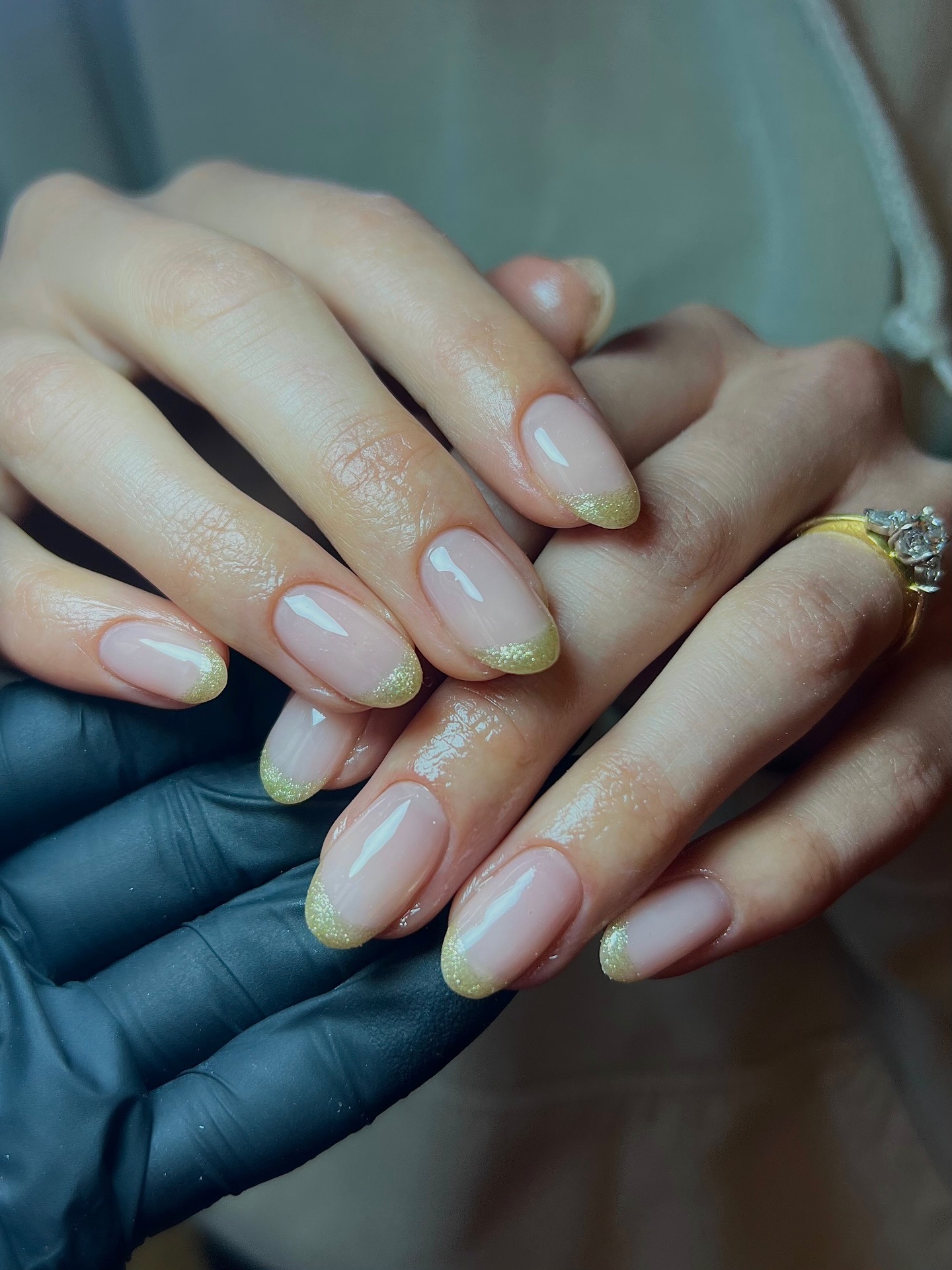 A close-up shot of a glittery, gold French manicure