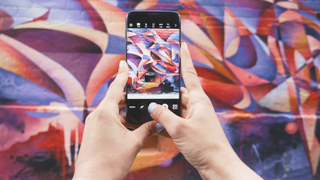 Man photographing a brightly painted wall with a cameraphone