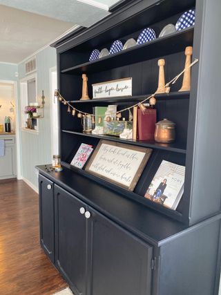 Black built-in dining room hutch with recipe books, candle sticks and more decor