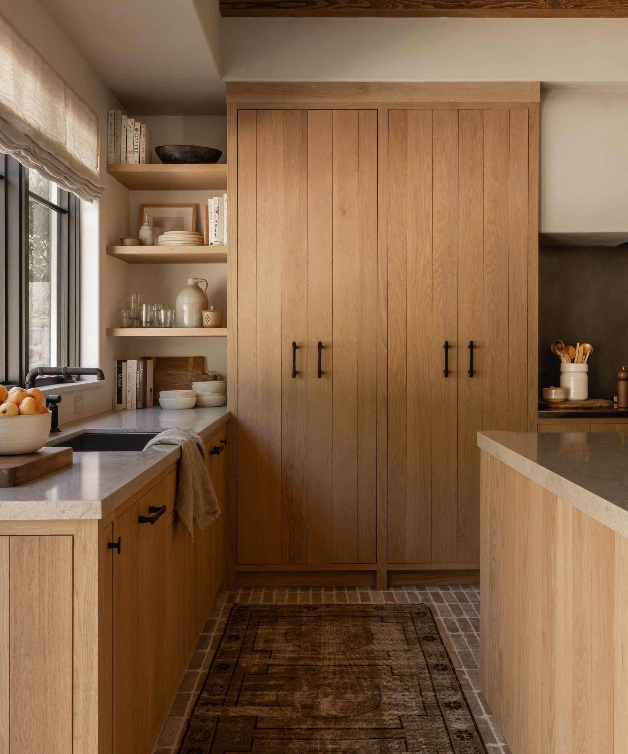 A wooden kitchen with shiplap-style cabinets, stone countertops and a brick floor