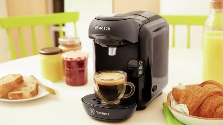 image of a Bosch Tassimo coffee machine, with a full cup of coffee and bread and croissants around it