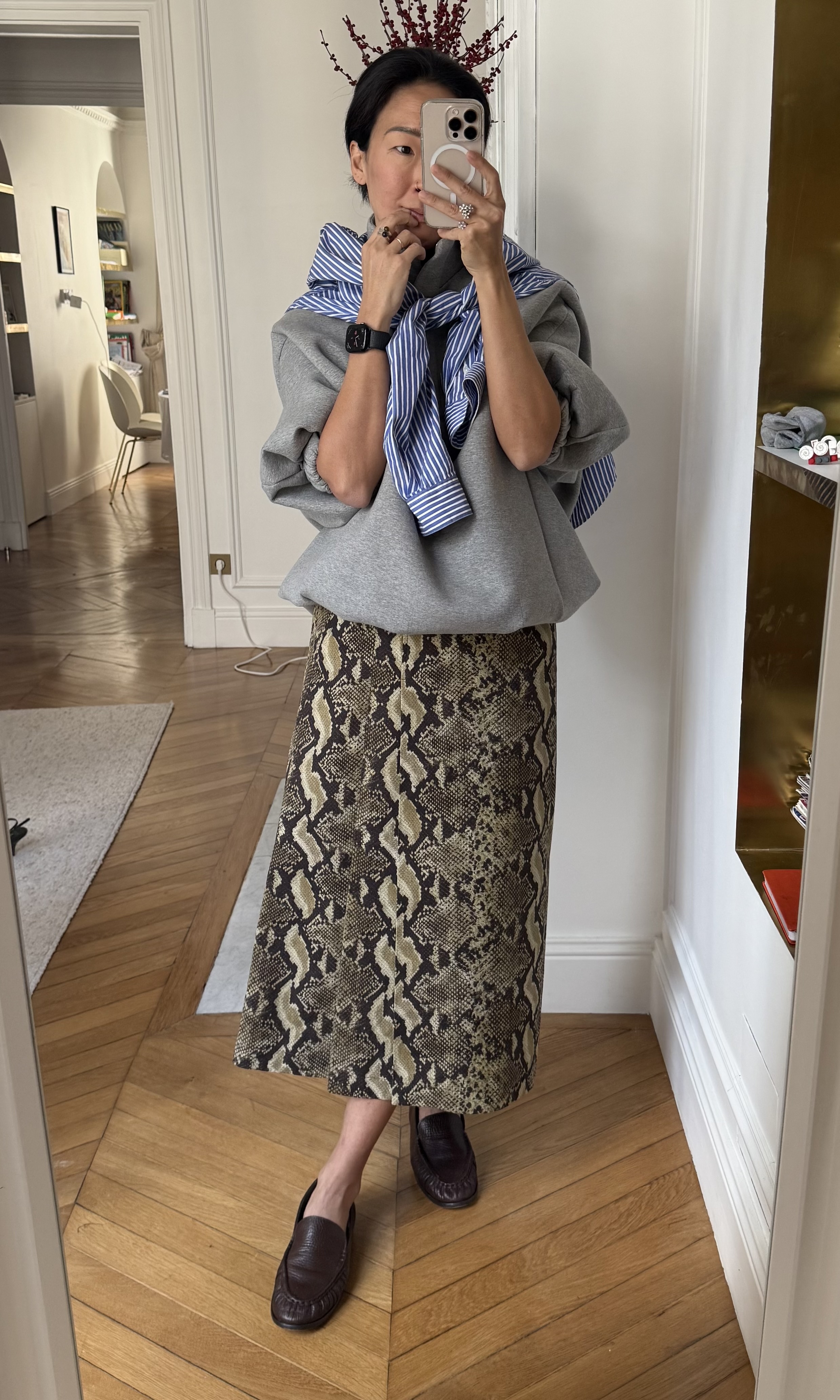 Irene Kim styles a snakeskin skirt with an oversized sweatshirt, stripy button-down and loafers