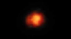 A fiery orange smudge representing Maisie's galaxy, one of the earliesrt galaxies in the known universe