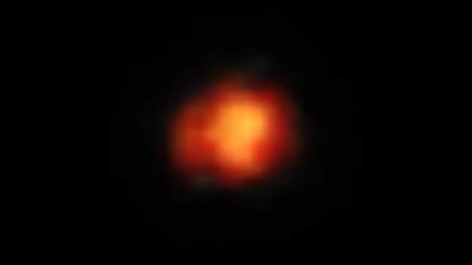 A fiery orange smudge representing Maisie&#039;s galaxy, one of the earliesrt galaxies in the known universe