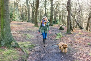 Woman taking puppy for walk in forest - stock photo