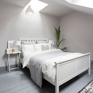 bedroom with white wall and wooden floor and bedside table