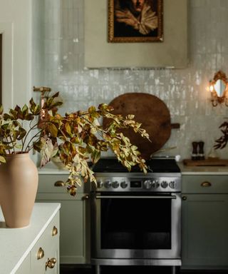 cozy green kitchen with antique decor and fall foliage in a terracotta vase