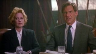 Melanie Griffith and Harrison Ford sit in a heated boardroom discussion in Working Girl.
