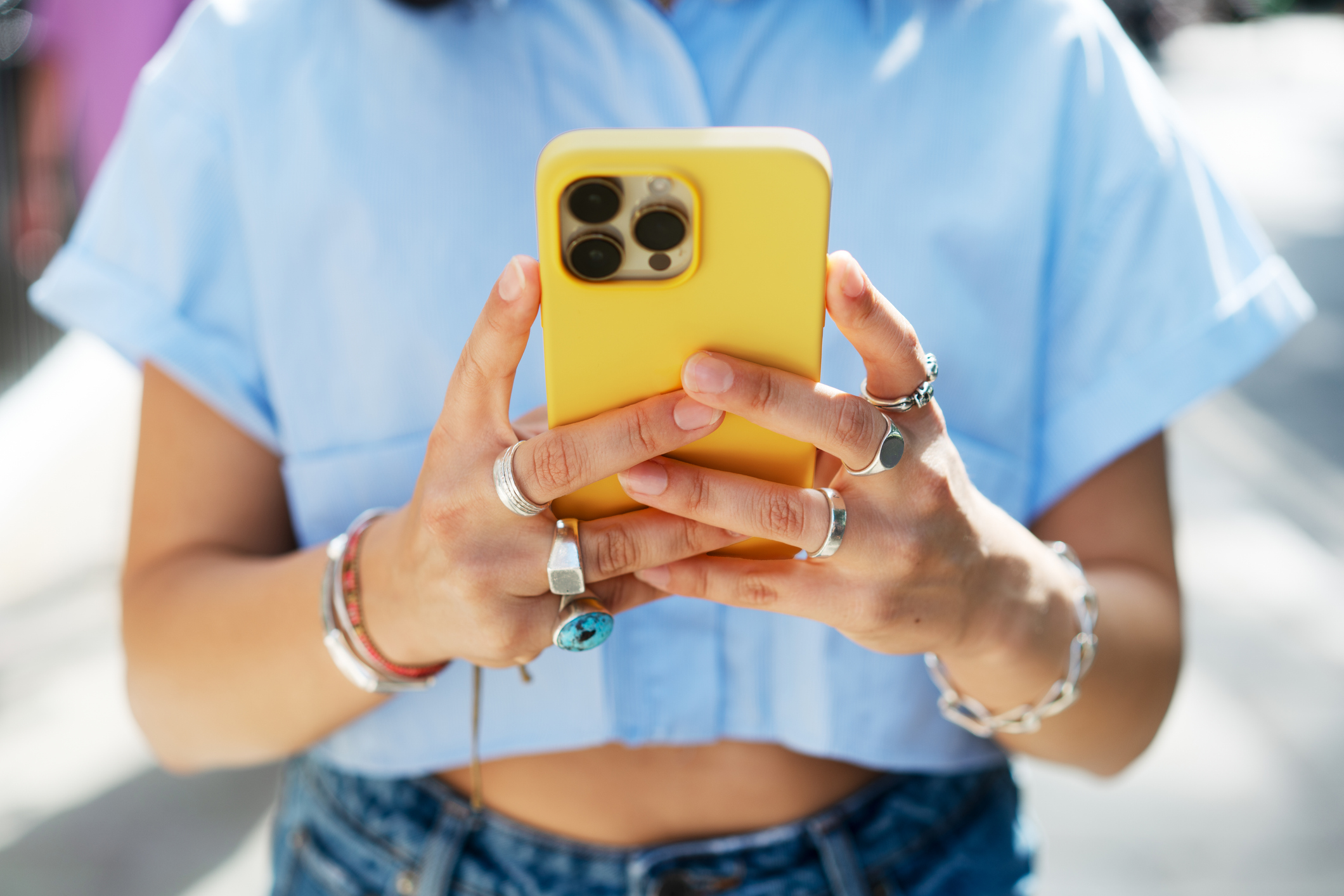 A person using their phone with a yellow phone case. 