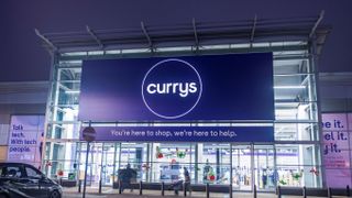 The front of a Currys store with a car parked in a nearby space