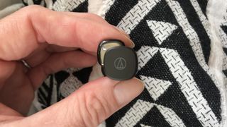 Audio-Technica ATH-SQ1TW earbuds with LED illuminated on black and white background