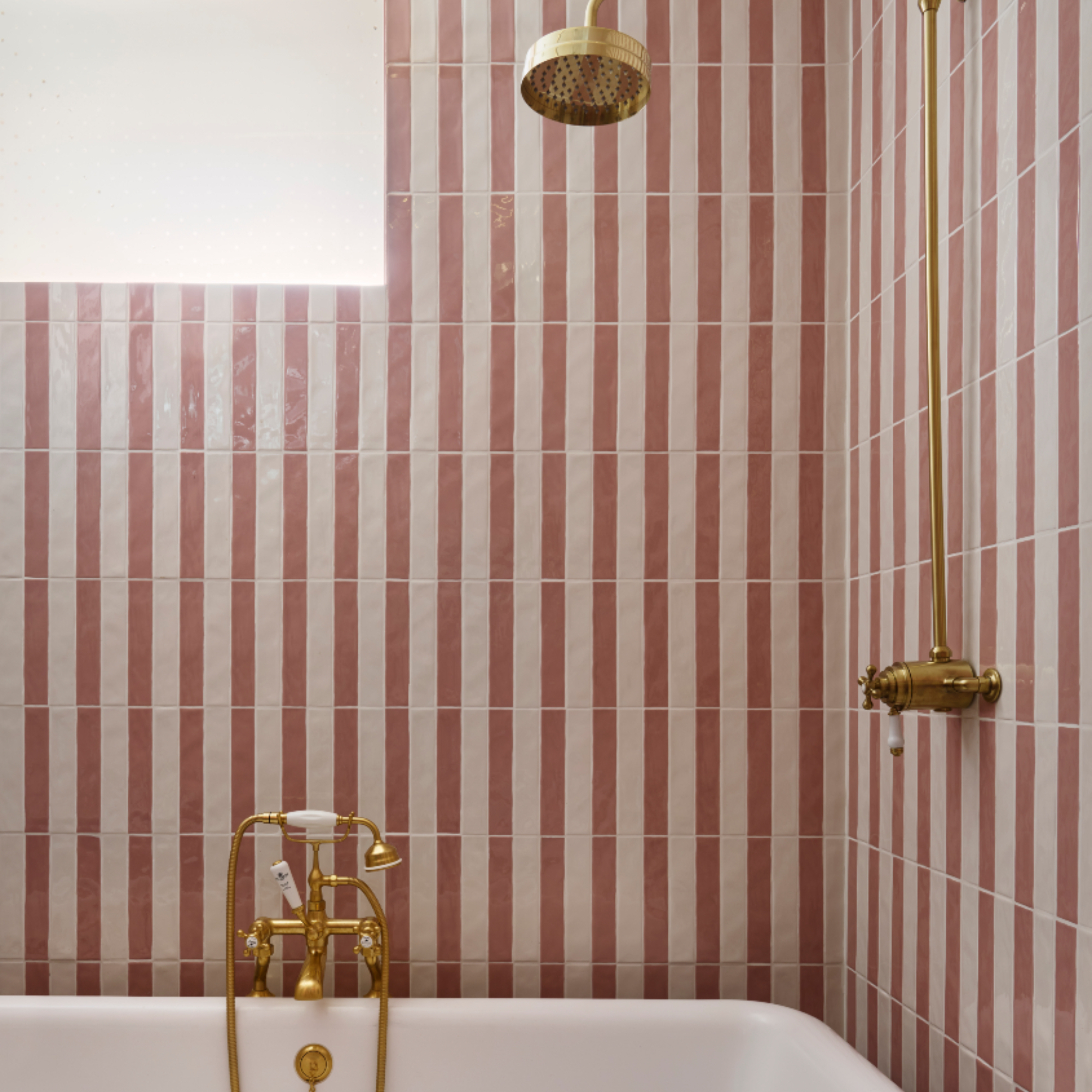 Pearl Lowe's bathroom with pink and white tiles, brassware, shower over bath