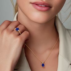 Model wearing a gold necklace and ring with blue lab grown diamond sold at Angara