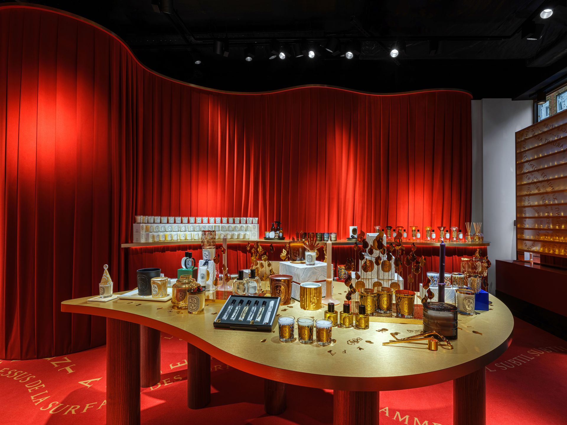 Diptyque Marylebone pop-up shop with red curtains and a golden table