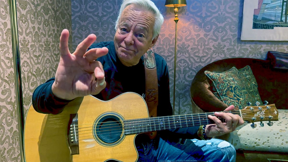 Tommy Emmanuel poses in a San Francisco hotel room with his custom Maton acoustic guitar (Maton TE Personal — TE for Tommy Emmanuel), a cutaway model he uses as his main guitar. It has back and sides of Queensland maple and a spruce top. 