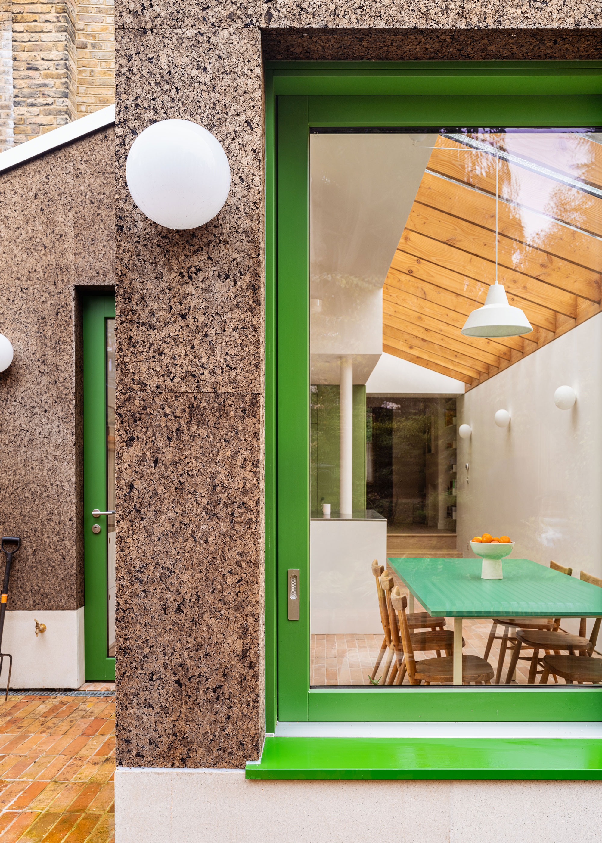 cork clad extension with green framed windows and doors