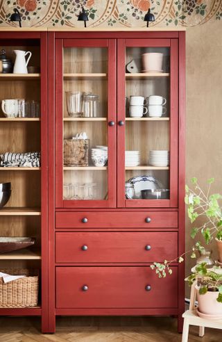 Red wooden cabinet with open and closed shelving and storage, country kitchen aesthetic, shelf filled with kitchenware