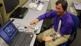 A photo of Kevin Warwick using his cyborg implant to control a robot hand over the internet.