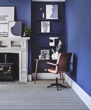A living room with cobalt blue wall paint decor with alcove study area and striped grey carpet floor decor