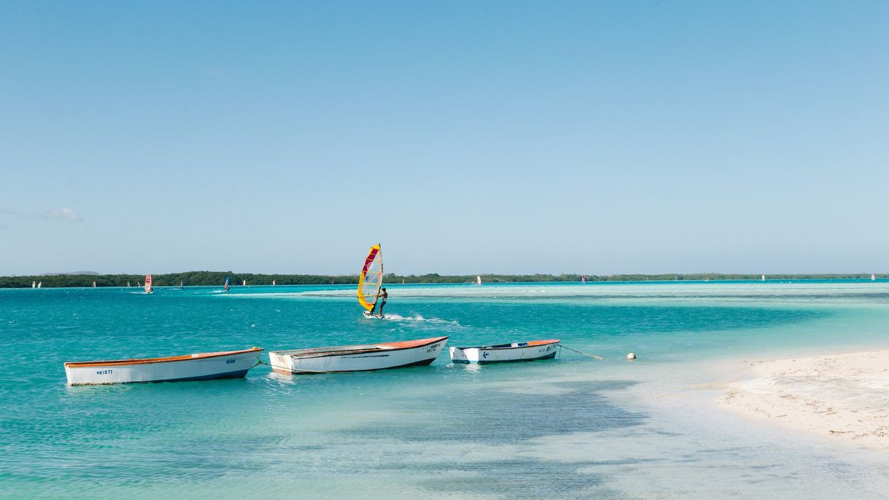 kitesurfer and small boats on the blue shore of Bonaire