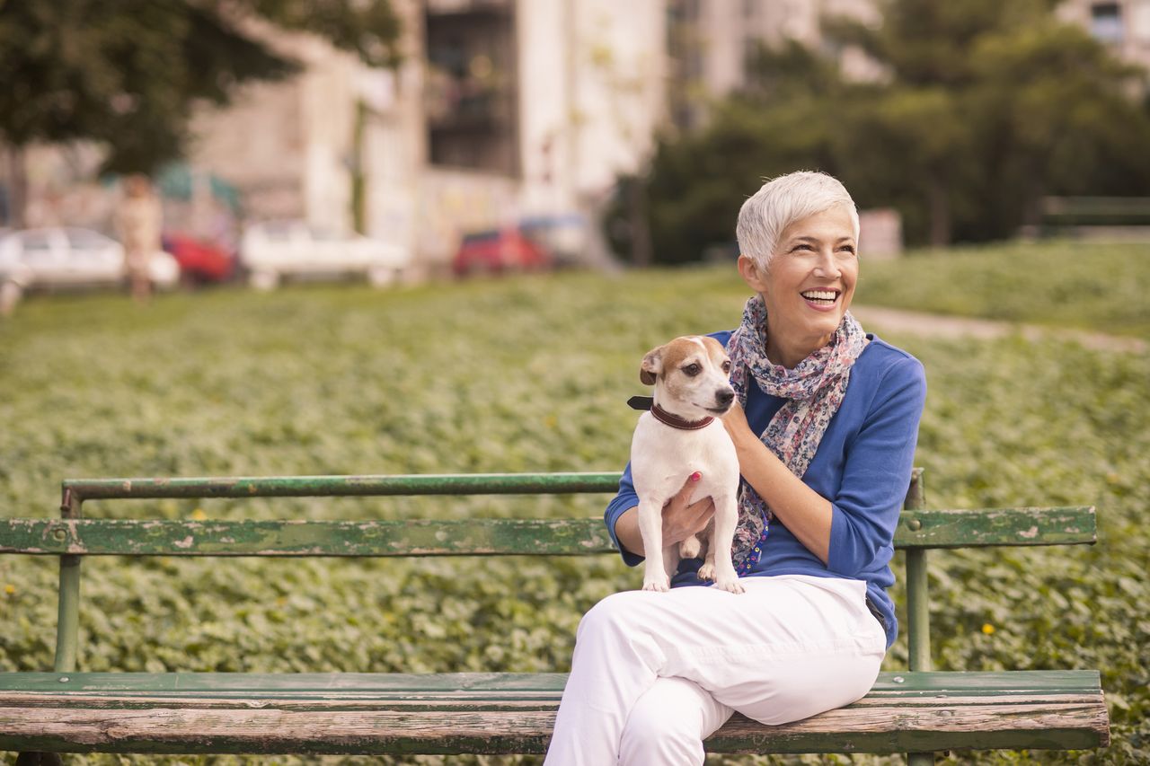 Older woman on park bench holding dog