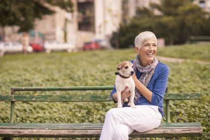 Older woman on park bench holding dog