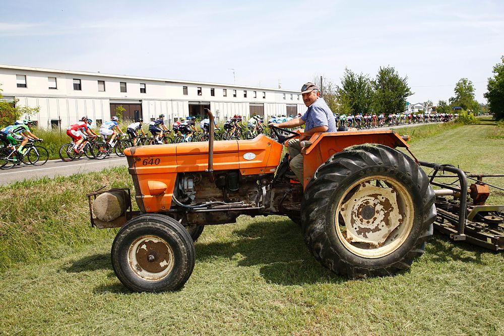 A farmer looks at the peloton during the 11th stage of the 99th Giro d'Italia