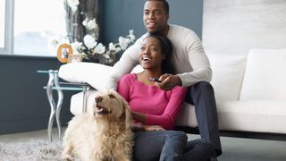 Couple watching TV with their dog