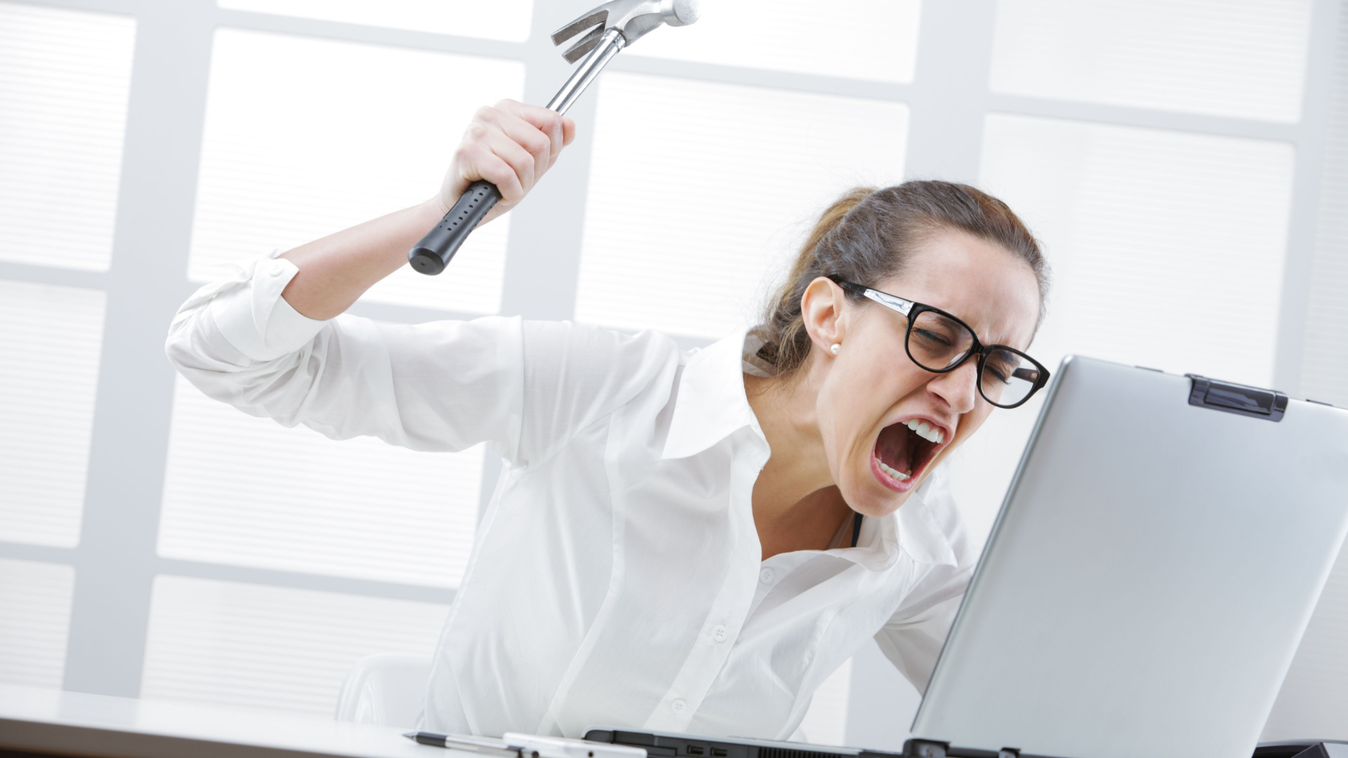 Mujer enojada con la PC sosteniendo un martillo