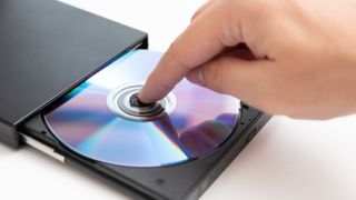 Someone&#039;s finger holding down a DVD disk in an external DVD player