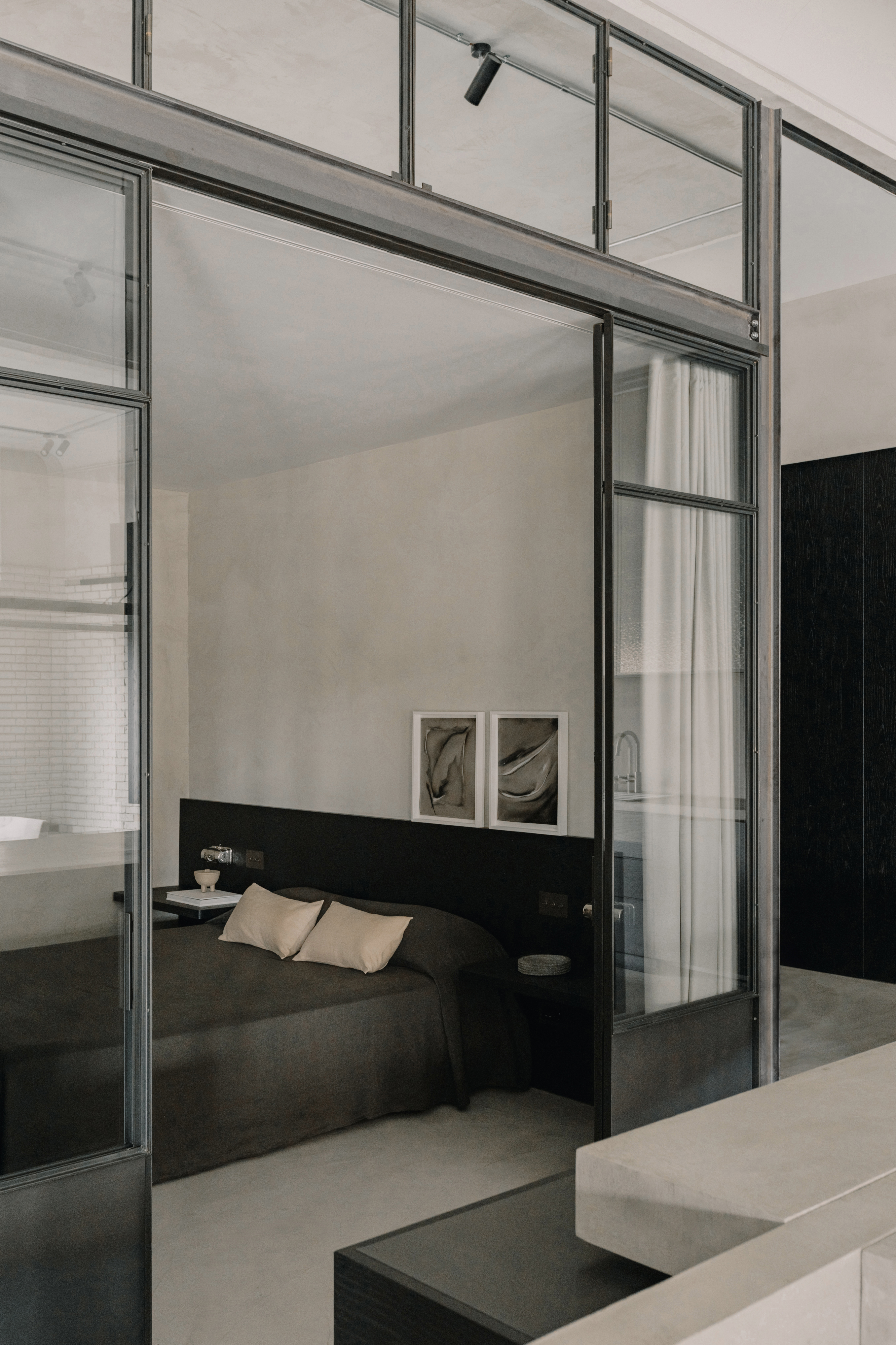 industrial bedroom in monochrome palette through a glass room divider