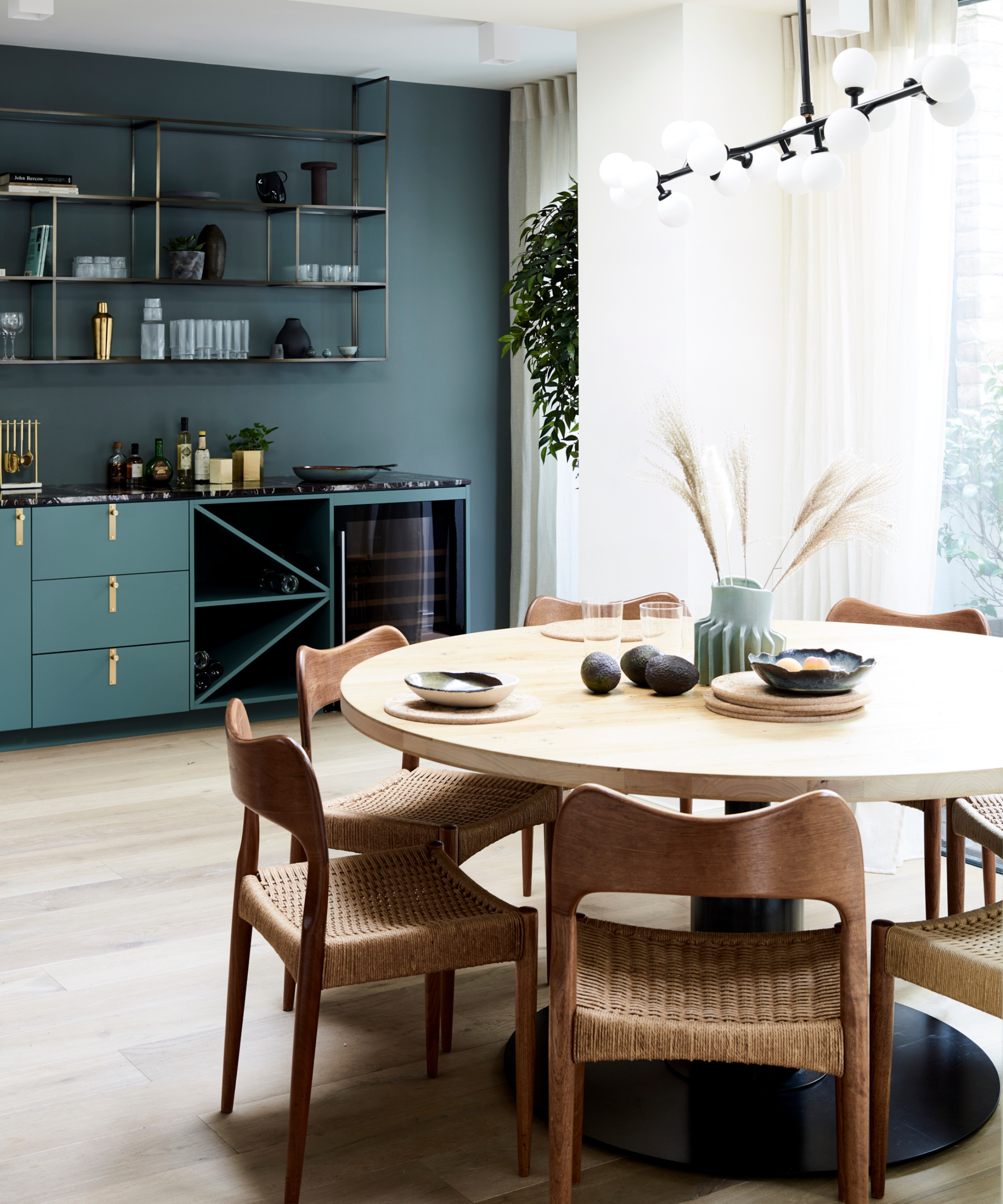 a dining room with a round wooden table with chairs around it, blue painted walls and blue cabinetry