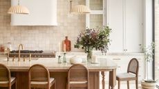 a white kitchen with zellige tile backsplash and classic wood island with flowers on