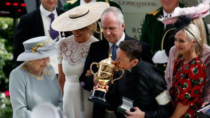 Queen Elizabeth II watches on as Italian jockey Frankie Dettori kisses the Gold Cup at Royal Ascot