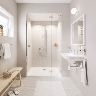 Neutral bathroom with light grey mozaic tiles, large in-built shower and a wooden bench against the wall under a window