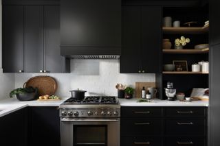 A kitchen with dark cabinets and shelves