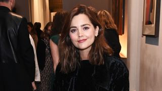 Jenna Coleman with her hair wavy and a black top at a press night 