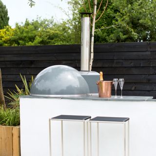 Slimline outdoor kitchen with bar stools and pizza oven