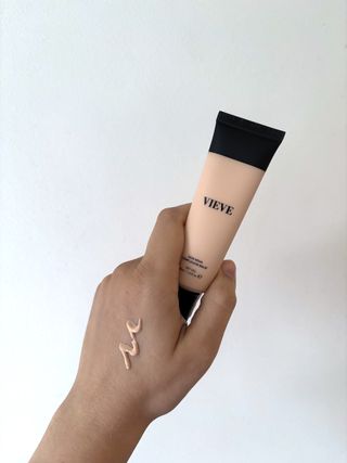 Mica Ricketts holding Vieve Skin Nova Complexion Balm with swatch of product